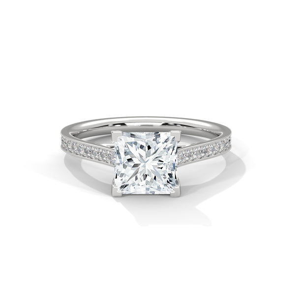 “Aria Ring—princess-cut diamond brilliance, sleek four-prong elegance, and pavé-band sparkle crafted to symbolize modern beauty, timeless love, and unforgettable moments.”