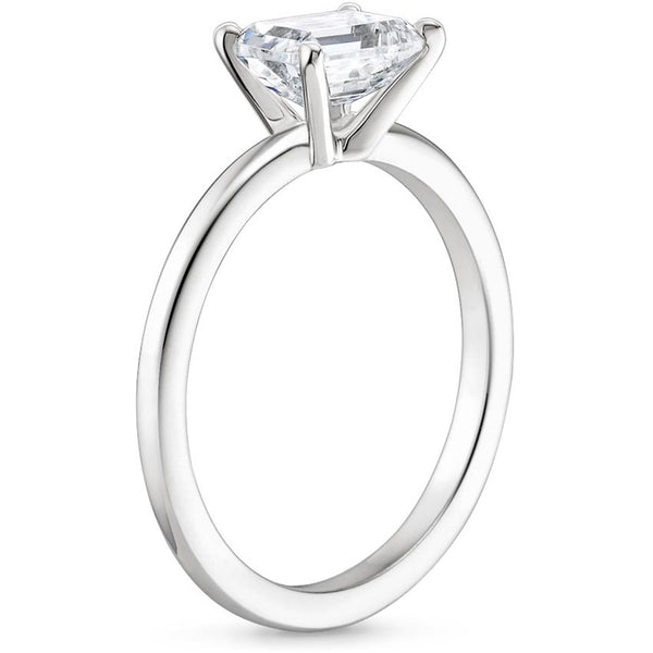 Solstice Grace is a minimalist masterpiece, showcasing an emerald-cut diamond in a classic four-prong setting with a smooth, polished band that radiates refined simplicity.