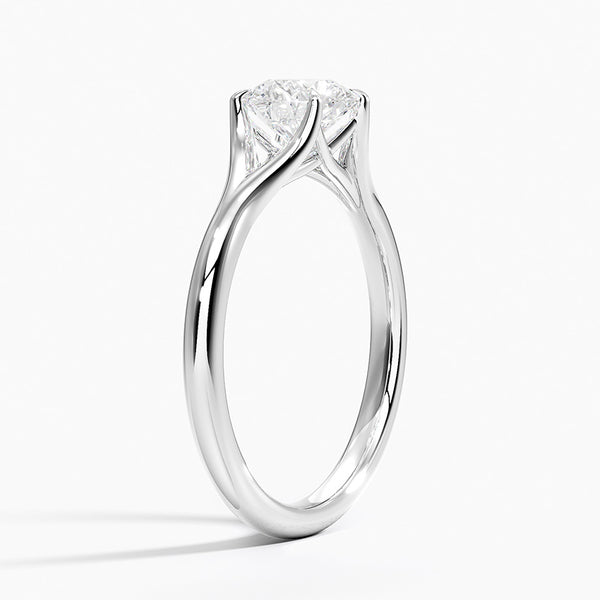 A modern solitaire with sculptural grace, the Seraphine Crest features elegantly arched prongs lifting a brilliant round diamond in a soft, sweeping embrace.