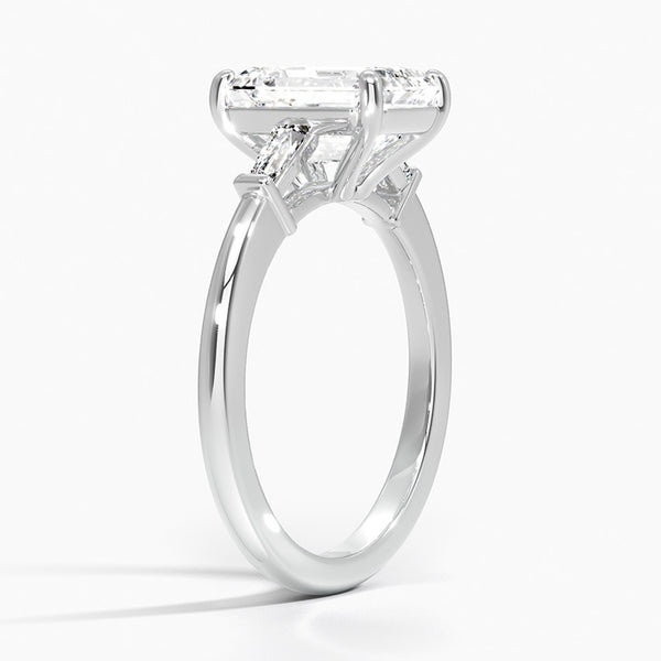 The Solmaris Crest ring showcases a commanding emerald-cut diamond framed by trapezoid side stones, exuding modern elegance and architectural beauty.