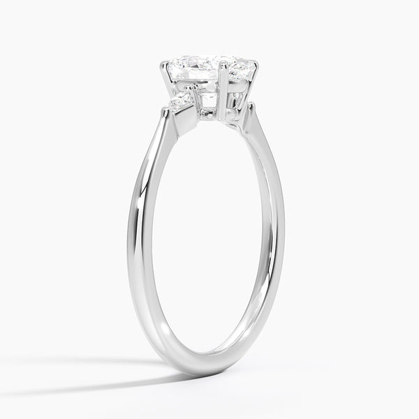 An icy-sleek three-stone ring crowned with a dazzling oval diamond that gleams like winter sunlight.