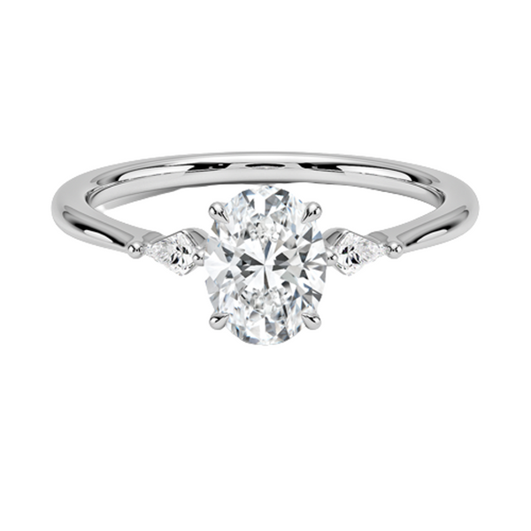 An icy-sleek three-stone ring crowned with a dazzling oval diamond that gleams like winter sunlight.