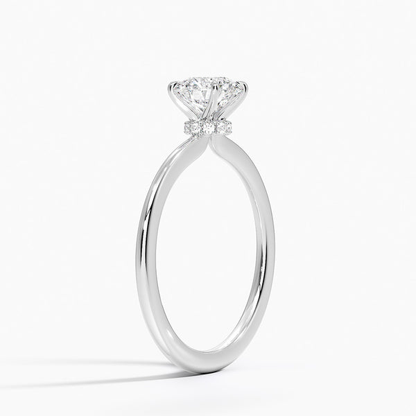 Celestia Crown radiates refined luxury, with a hidden halo of diamonds encircling the base of a dazzling round center stone in a sleek white metal setting.